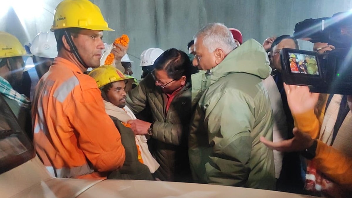 Ministro Principal de Uttarakhand, Pushkar Singh Dhami (C) y Ministro de la Unión, VK Singh (R), felicitan al primer trabajador rescatado dentro del túnel