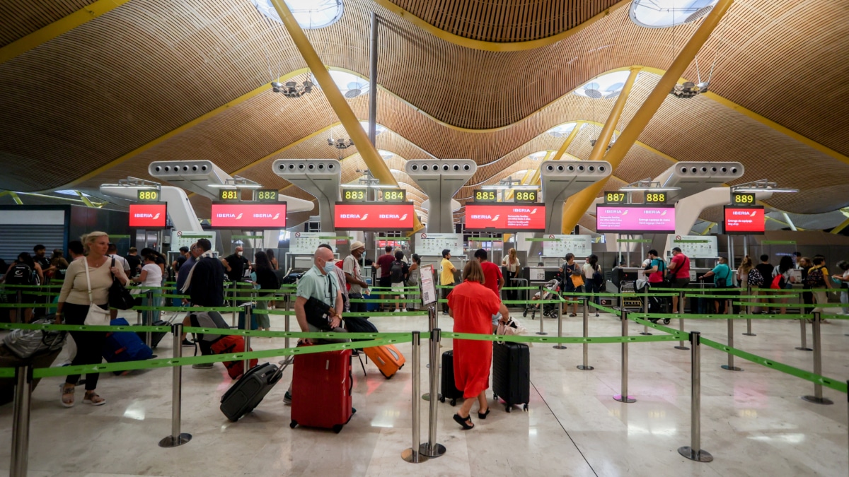 Varios pasajeros esperan para obtener sus tarjetas de embarque y facturar su equipaje en el día en que ha dado comienzo una huelga de los tripulantes de cabina de Iberia
