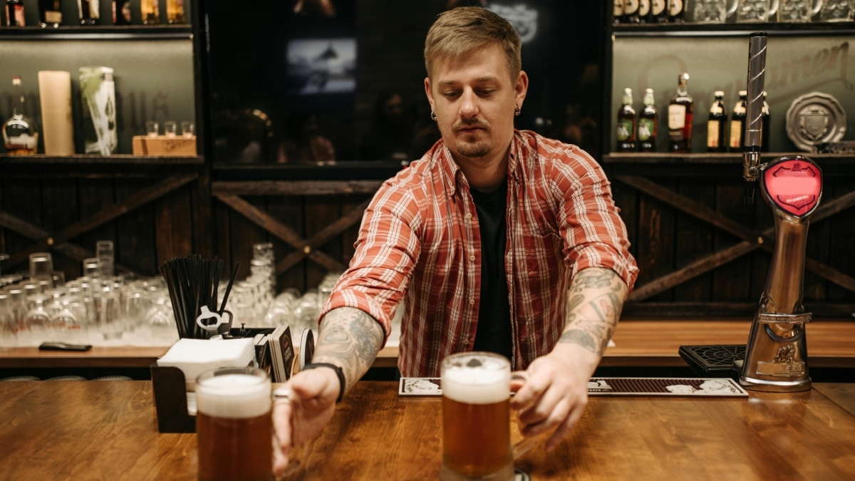 Un camarero joven sirve unas jarras de cerveza.