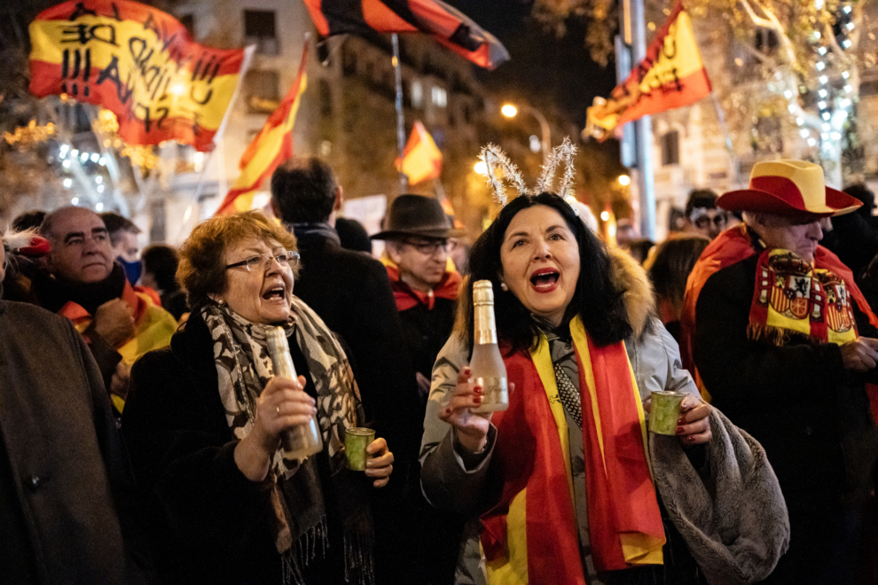 Decenas de personas con bufandas y banderas de España celebran la entrada del año nuevo, en la calle Ferraz