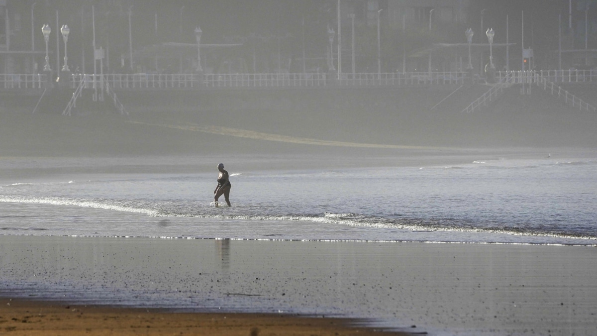 Una mujer se da un baño en la playa de San Lorenzo, el último sábado del año en Gijón.