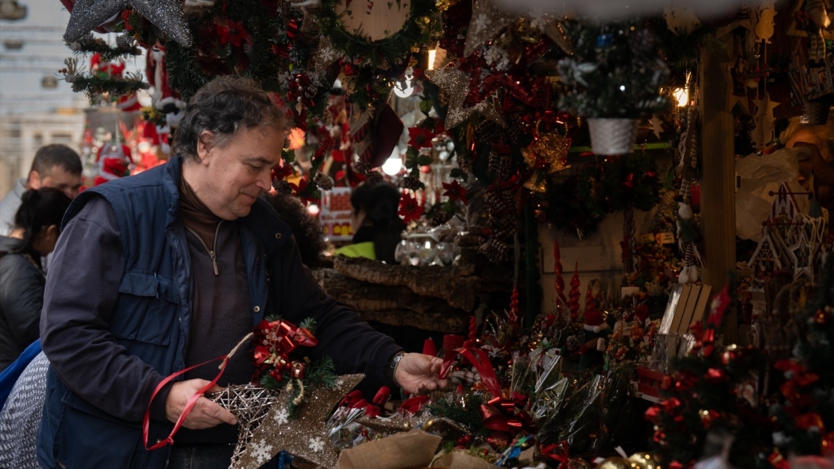 Un hombre atiende en su puesto del mercadillo navideño de la Fira de Santa Llúcia, en Barcelona.