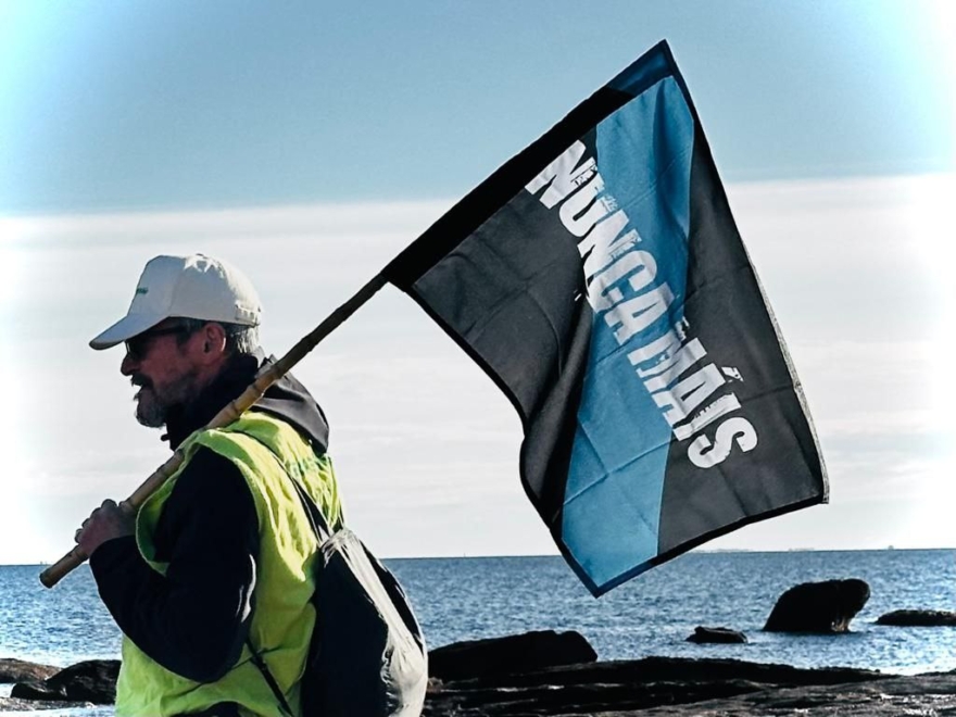 Un voluntario de Greenpeace con la bandera de Nunca Mais durante la limpieza estos días de las playas gallegas.