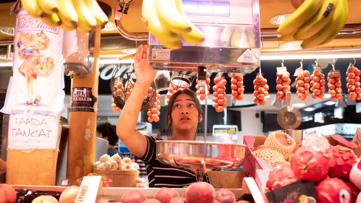 Una persona trabaja en un puesto de fruta en el mercado.