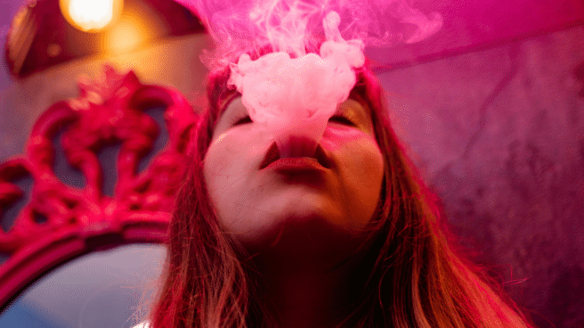 Chica fumando de tabaco calentado y echando humo
