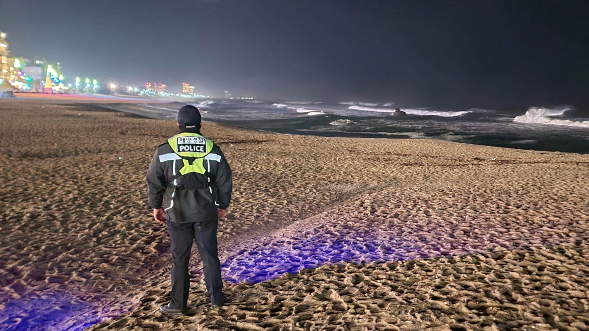 Un oficial de policía marítima patrulla una playa en Gangneung, mientras pequeñas olas de tsunami golpean las aguas de la provincia
