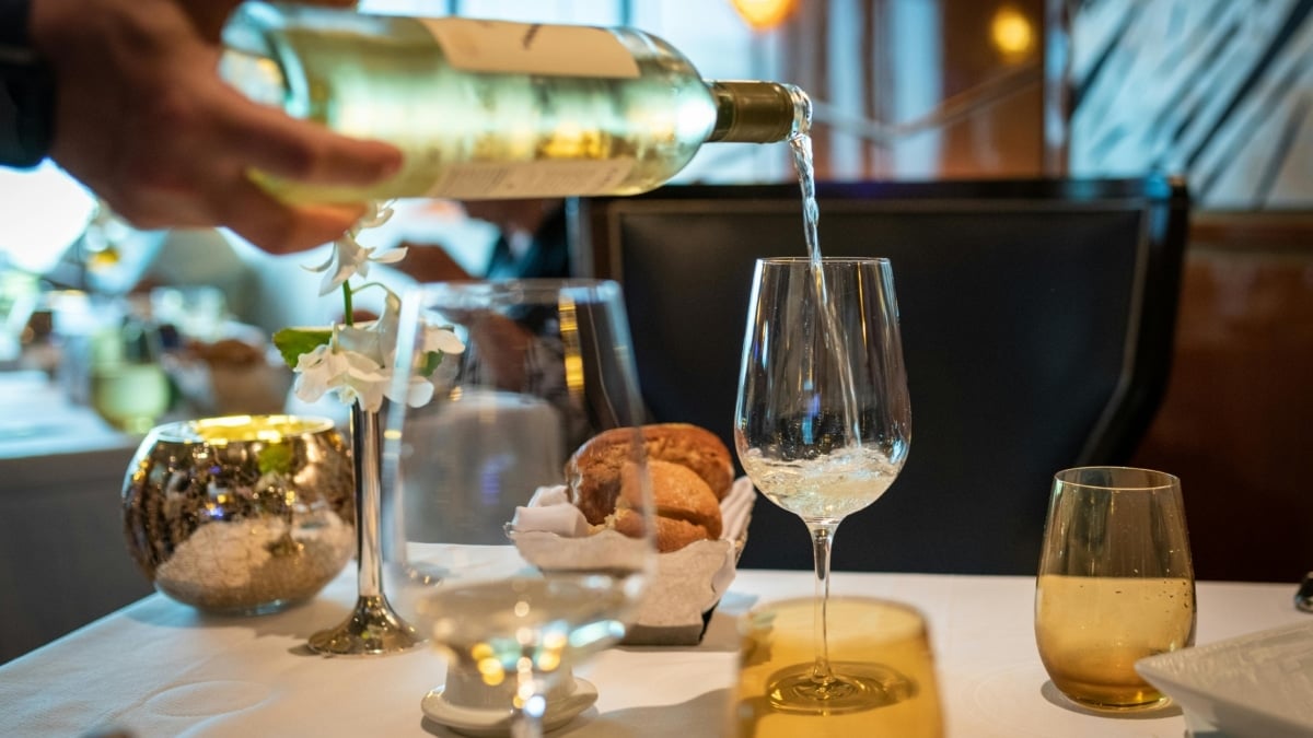 Una persona sirve un vino blanco en una copa.