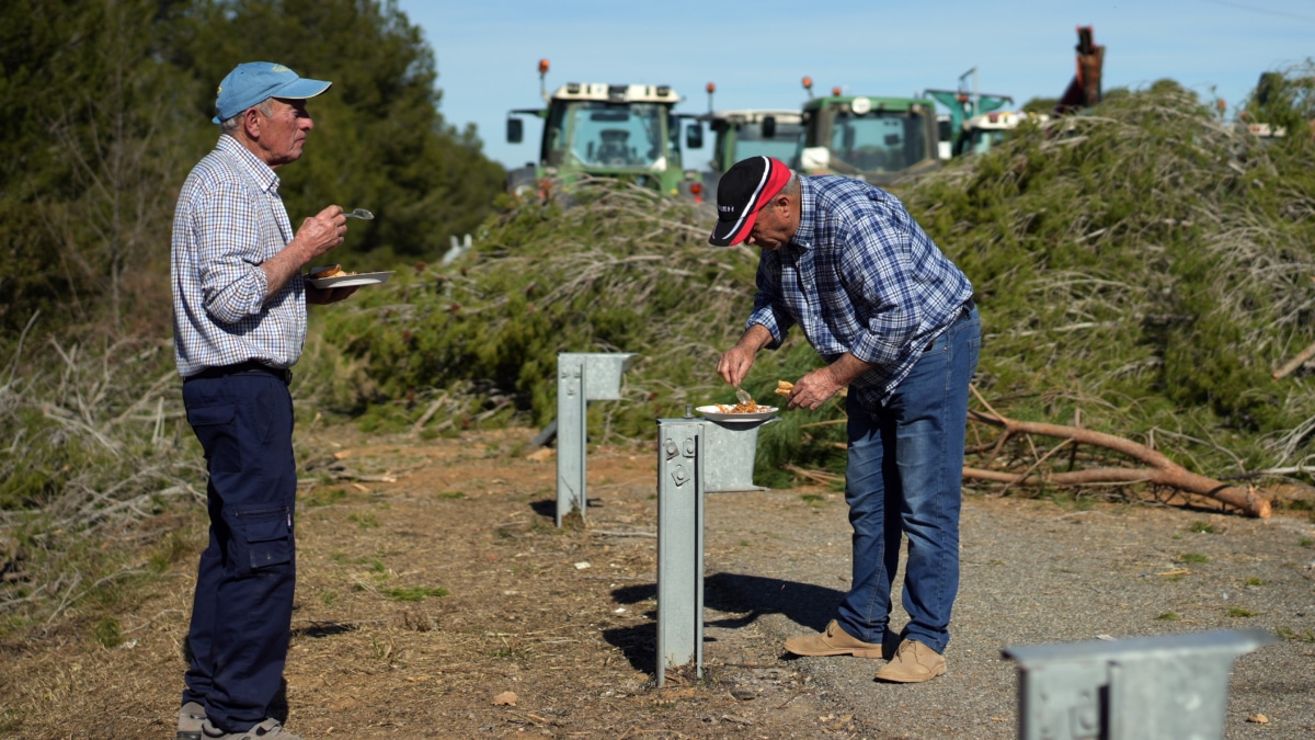 Dos agricultores comen durante el bloqueo en la autopista AP-7 en Pontós (Girona).