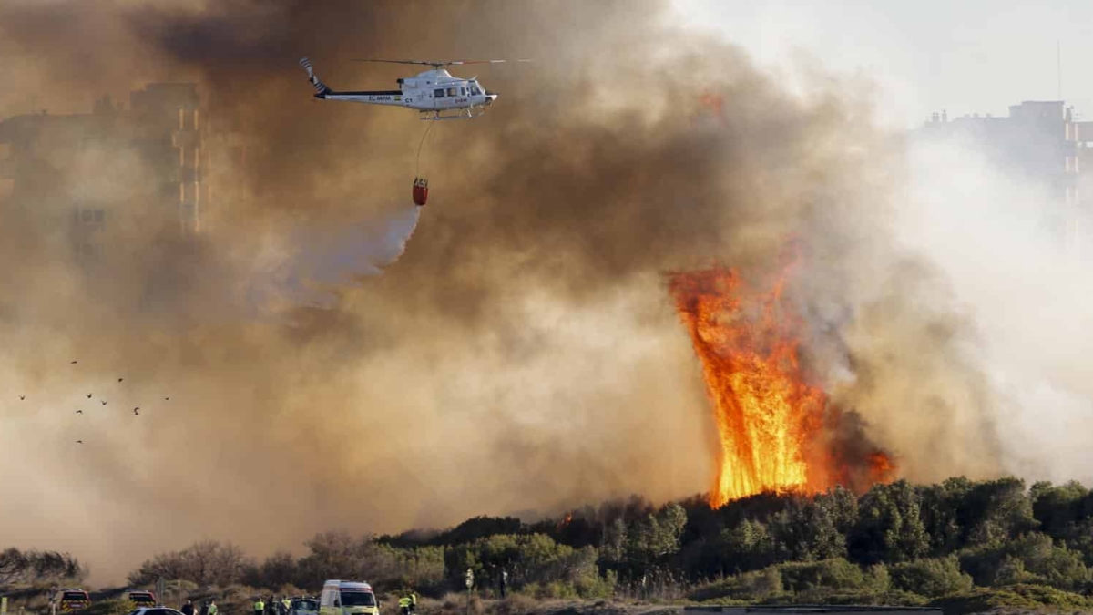 Un helicóptero sobrevuela el incendio de El Saler (Valencia).