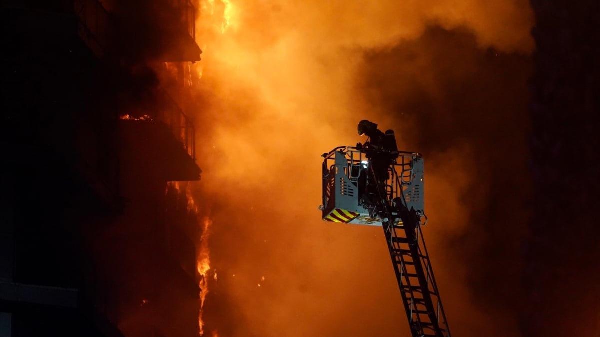 Un bombero trata de apagar el fuego en el edificio en llamas de Valencia.