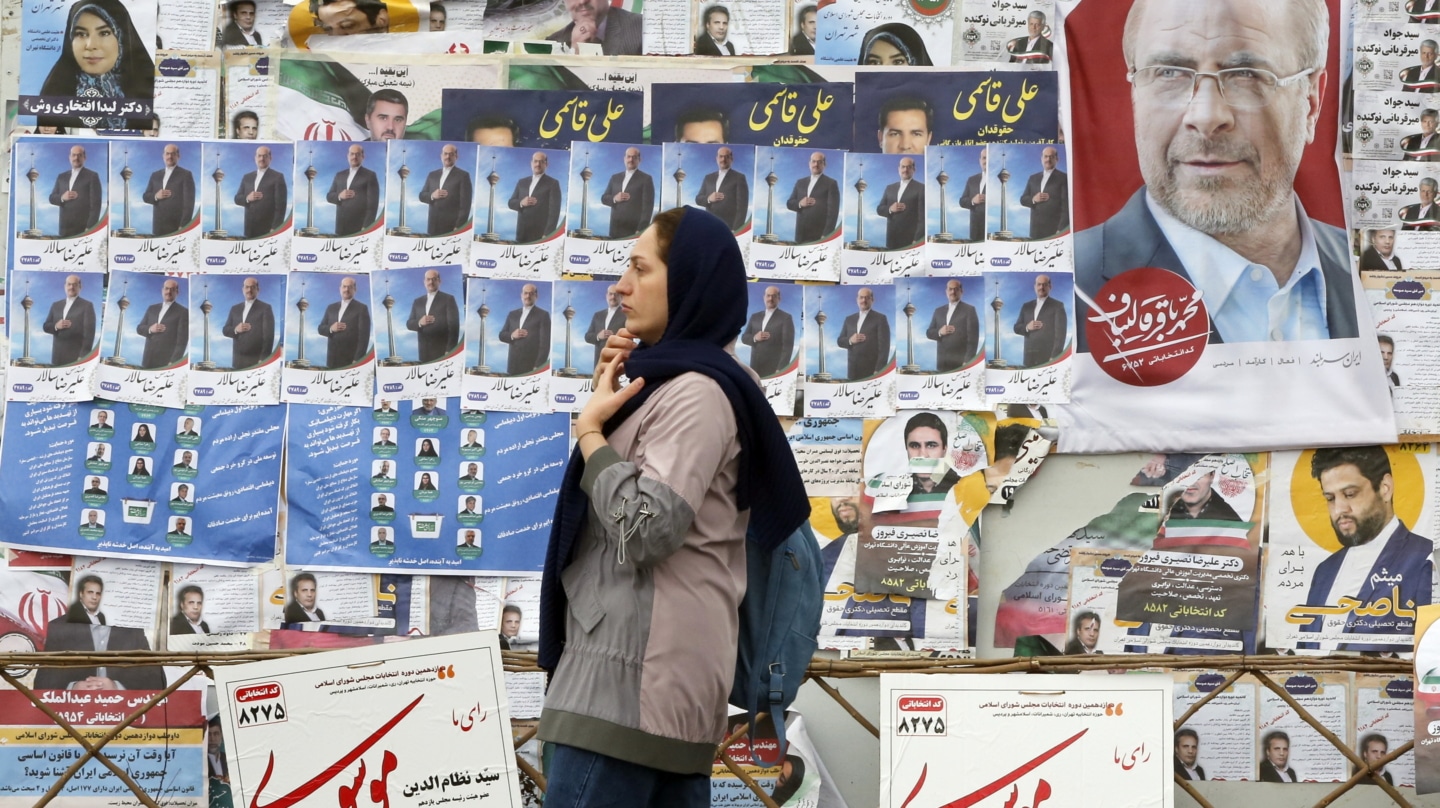 Una mujer pasa cerca de unos carteles electorales en Teherán