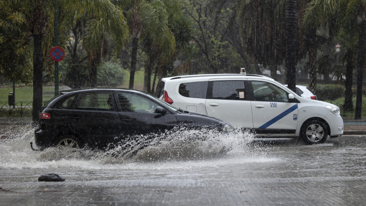 Varios coches circulan bajo la lluvia en la capital malacitana este sábado.