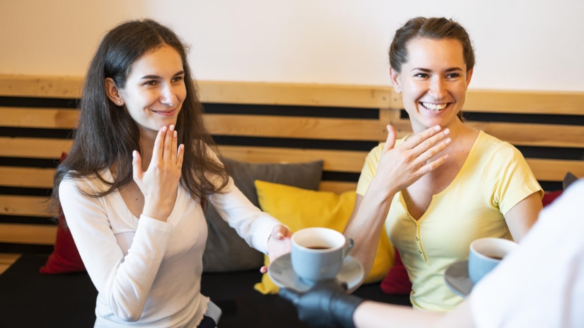 Dos mujeres hacen un gesto en lengua de signos.