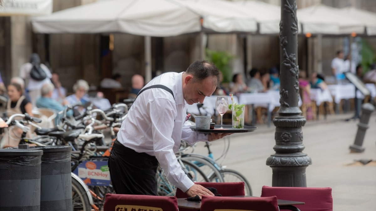 Un camarero limpia una mesa en la plaza Real de Barcelona