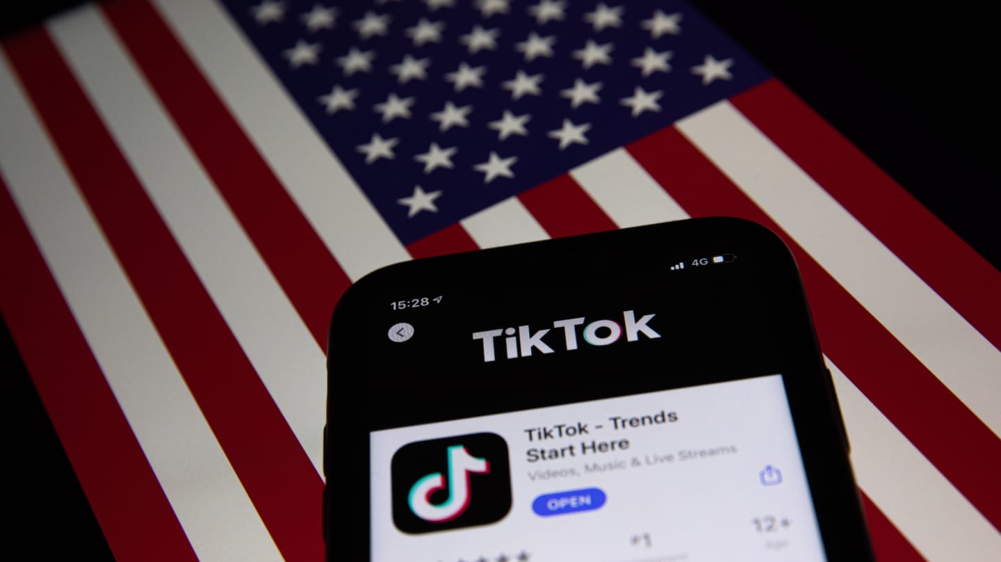 Un móvil con la aplicación de TikTok la bandera de EEUU de fondo
