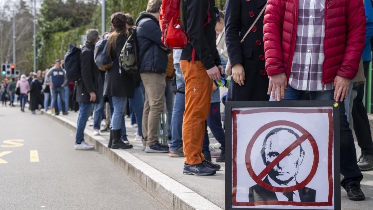 Un manifestante sostiene un cartel con una imagen tachada del presidente ruso Vladimir Putin