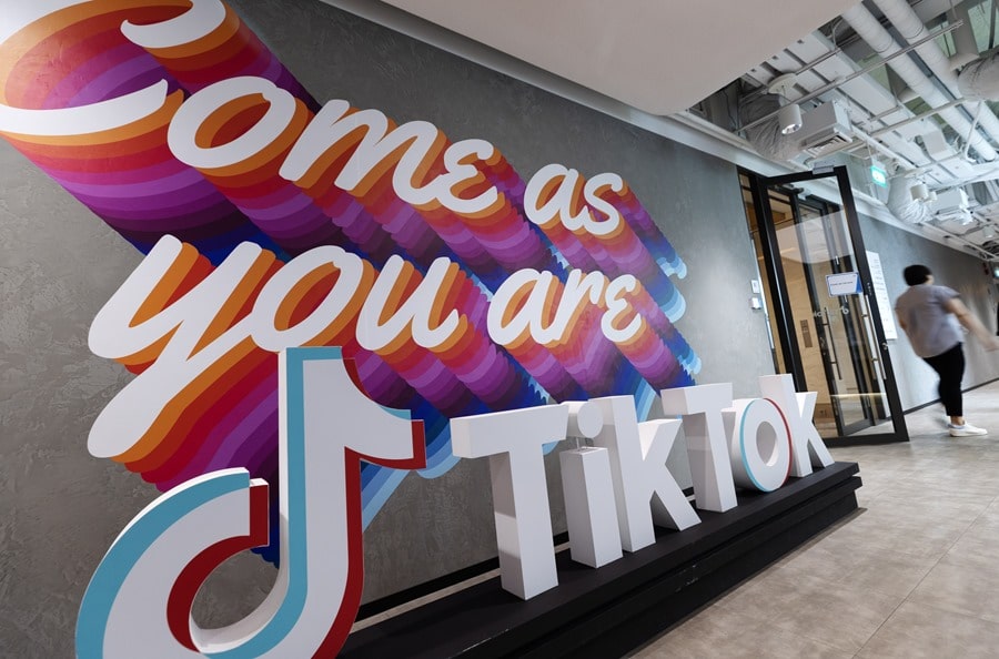 Un miembro del personal pasa por un cartel de TikTok en la oficina de TikTok durante una gira de prensa por las oficinas de Bytedance