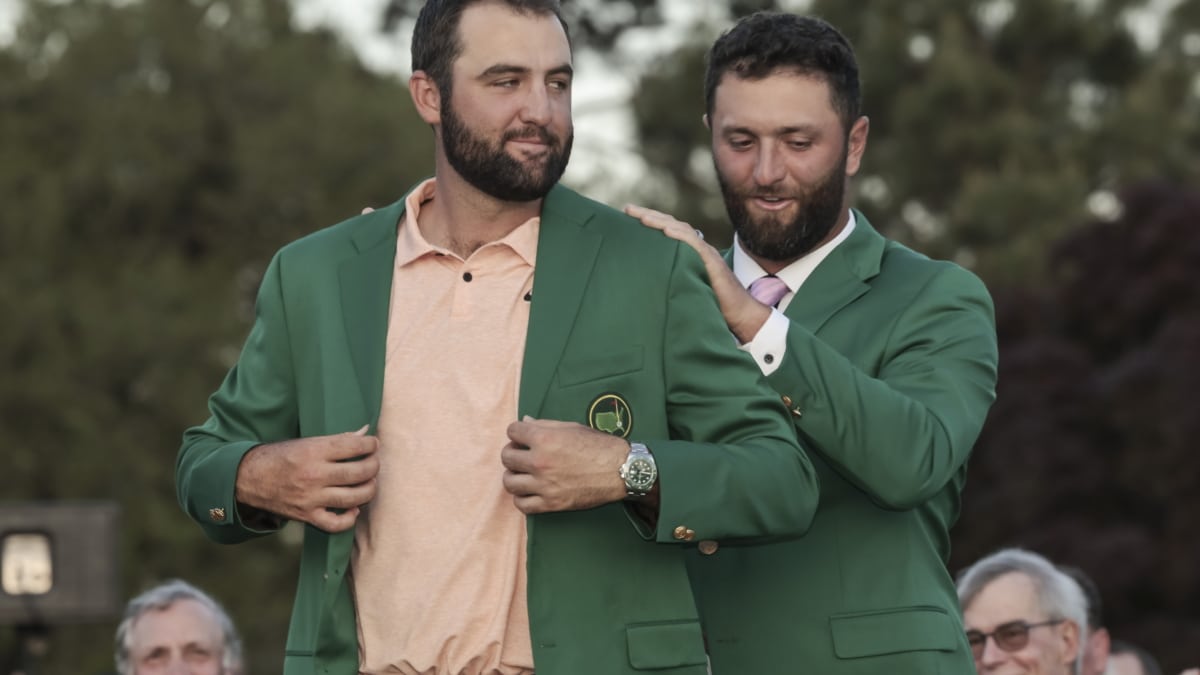 El golfista Scottie Scheffler de EE. UU. (izq.) recibe la tradicional chaqueta verde de manos del ganador del Masters del año pasado, Jon Rahm, después de ganar el Torneo Masters este sábado, en el Augusta National Golf Club