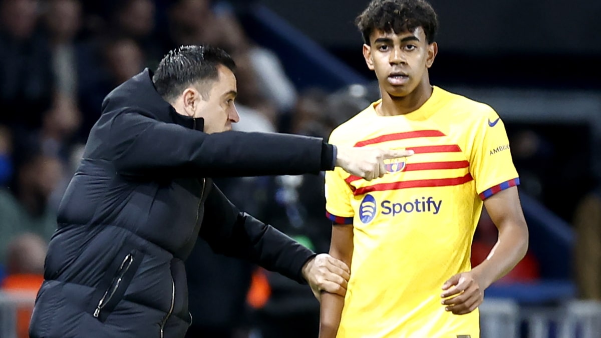 El entrenador del Barcelona Xavi Hernández (L) habla con el jugador Lamine Yamal