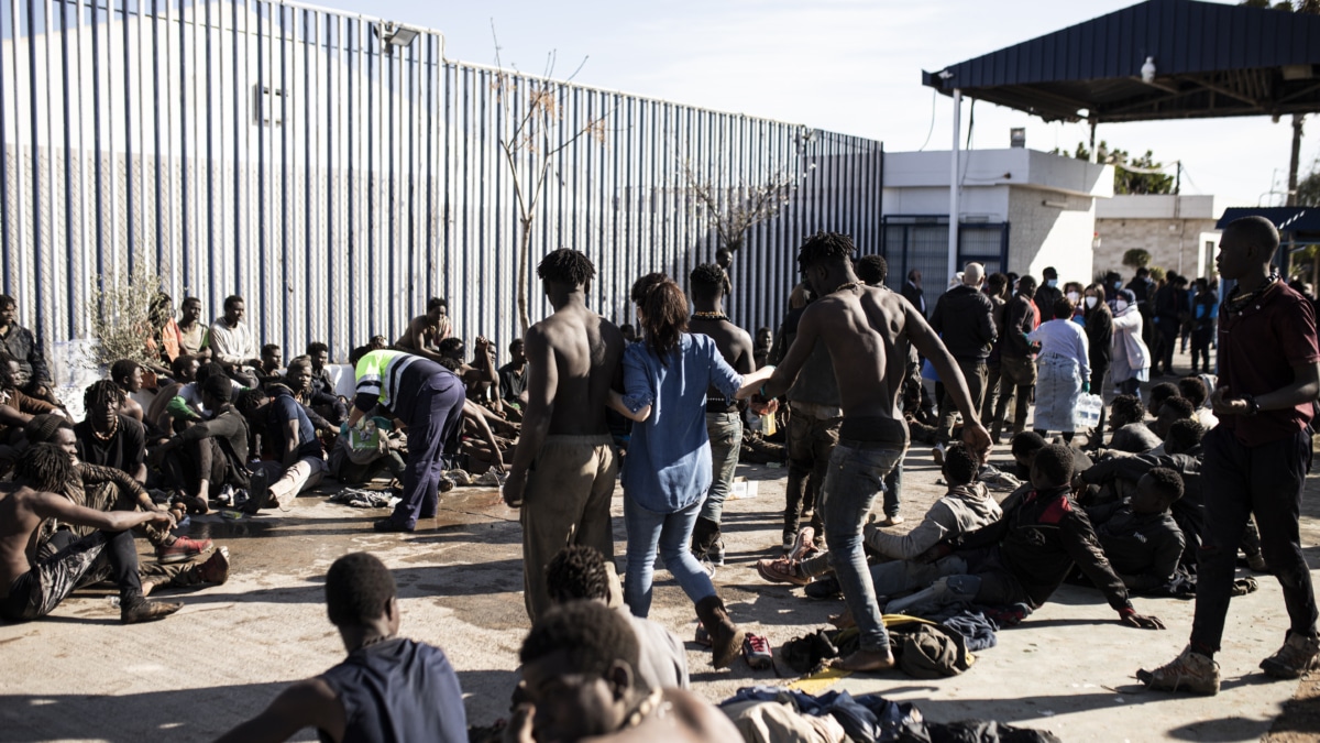 Una voluntaria acompaña a dos migrantes, tras saltar la valla de Melilla,