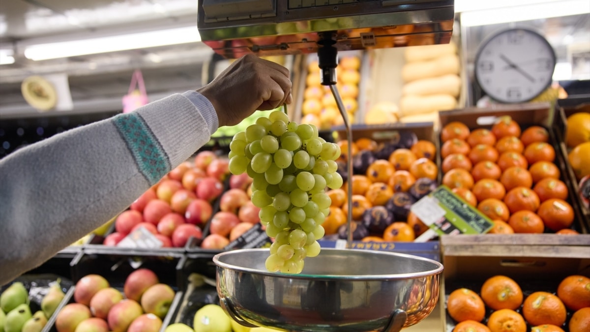 Un dependiente pesa un racimo de uvas en un mercado en Madrid.