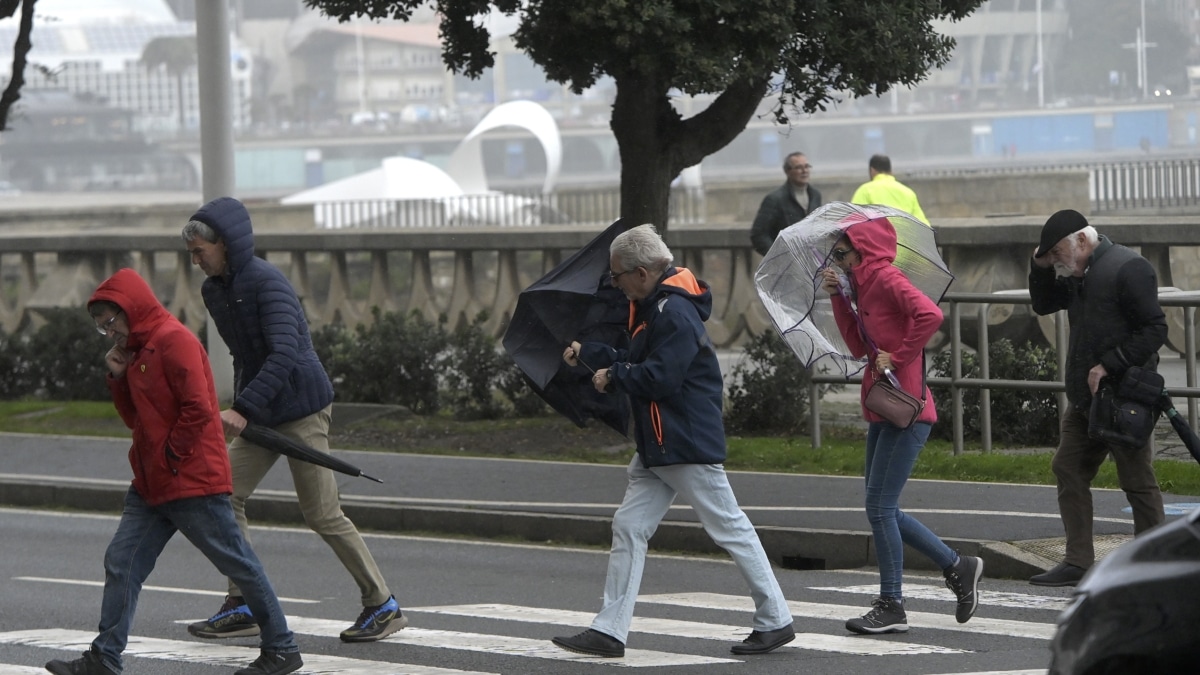 Varias personas se protegen de la lluvia y el viento con paraguas