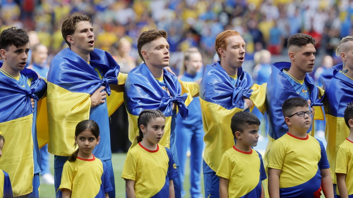 Los futbolistas de Ucrania entonan el himno nacional arropados por la bandera de su país