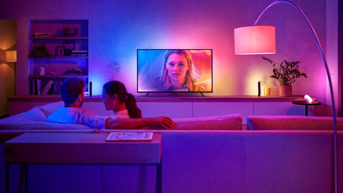Hombre y mujer sentados en el sofá con iluminación inteligente alrededor