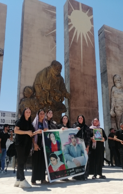 Mujeres yazidíes portando una pancarta con las fotos de víctimas 