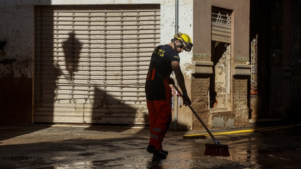 Un bombero realiza labores de limpieza en una calle cubierta de barro en Paiporta