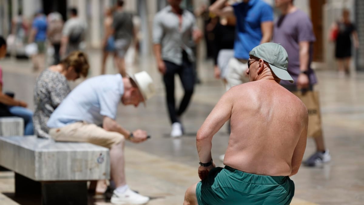 Un turista toma el sol sin camiseta en plena calle Larios este lunes en Málaga.