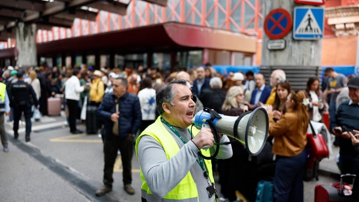 Un trabajador informa a los pasajeros de un AVE en la estación de Atocha, en Madrid.