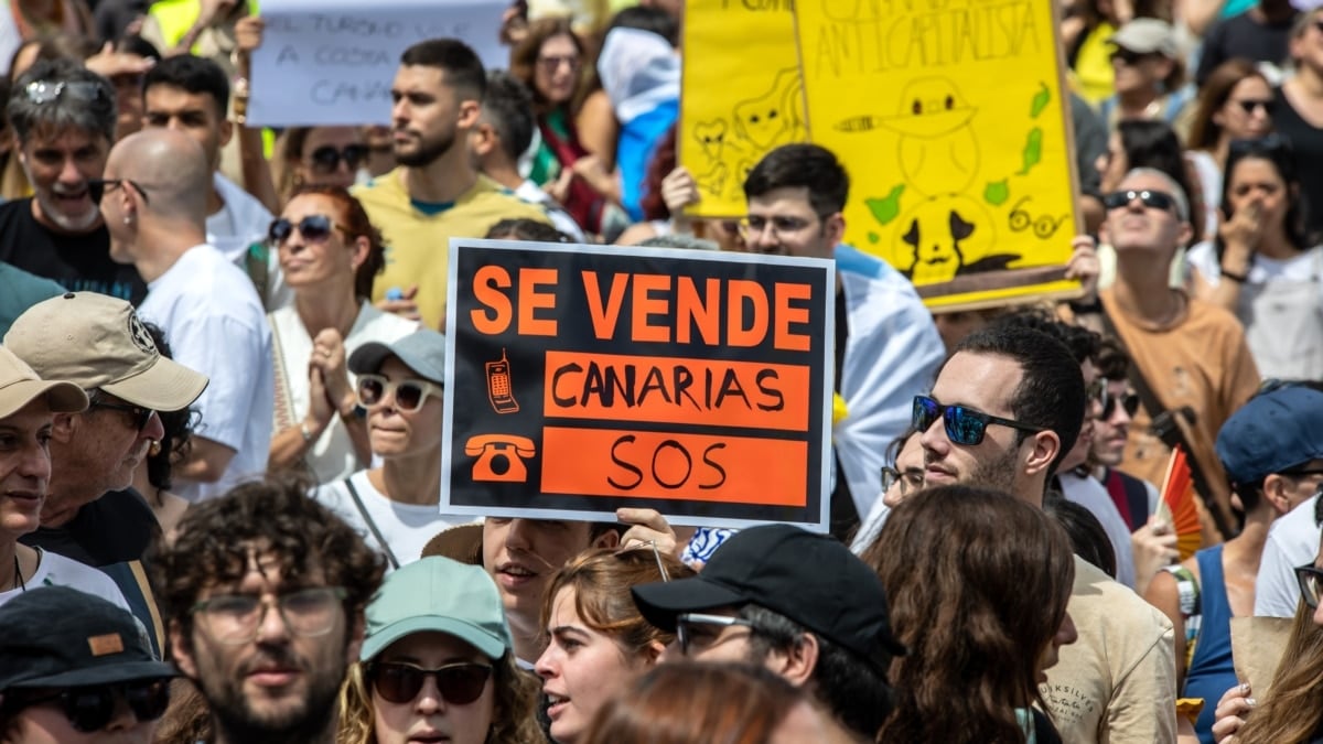 Decenas de personas protestan con carteles durante una manifestación contra el modelo turístico