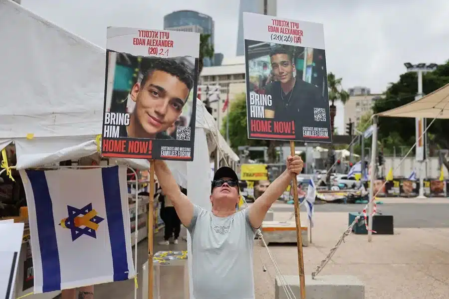 Un hombre sostiene fotos del soldado israelí-estadounidense Edan Alexander, en Tel Aviv