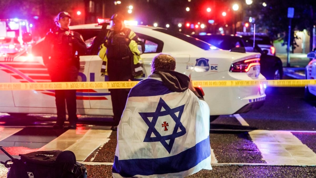 Un hombre envuelto en una bandera de Israel en el lugar de los asesinatos en Washington.