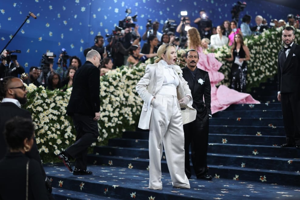 Madonna flanqueada por Haider Ackermann en la alfombra azul de la Met Gala.
