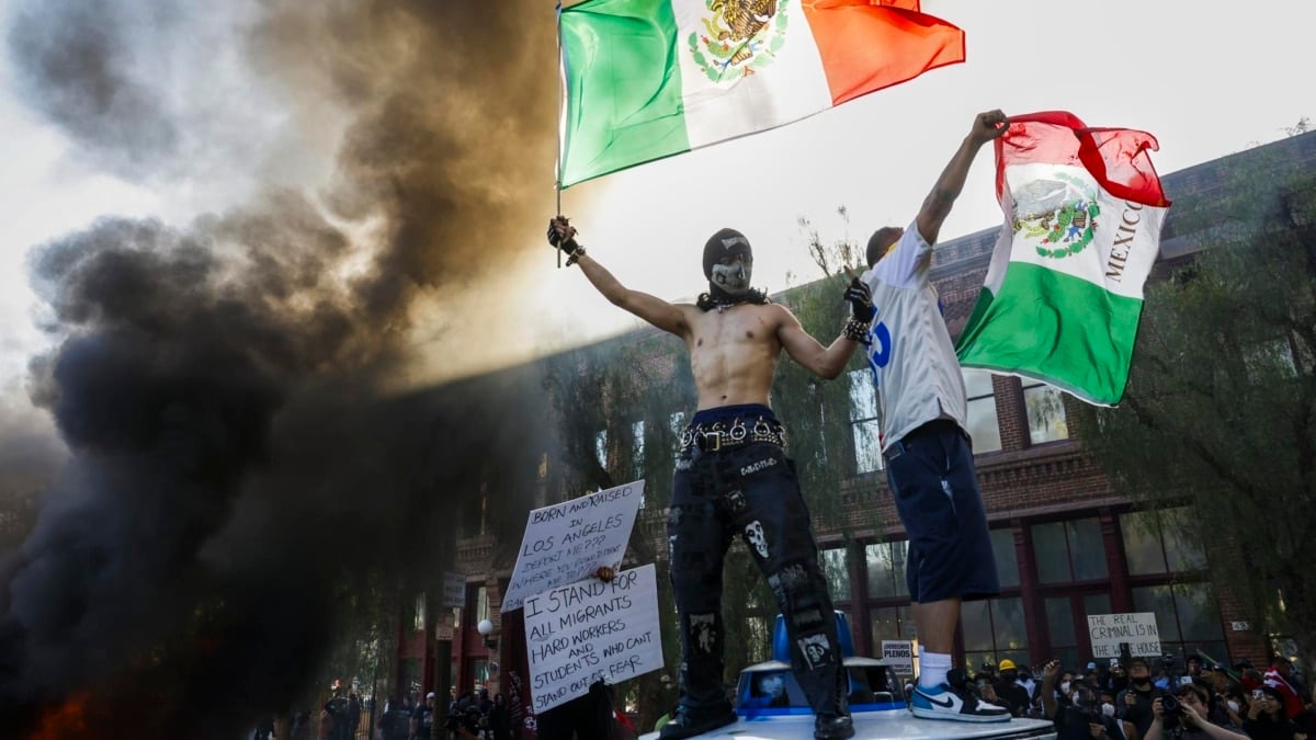 Manifestantes ondean banderas de México mientras coches arden en las protestas contra las redadas contra inmigrantes en Los Ángeles, California.