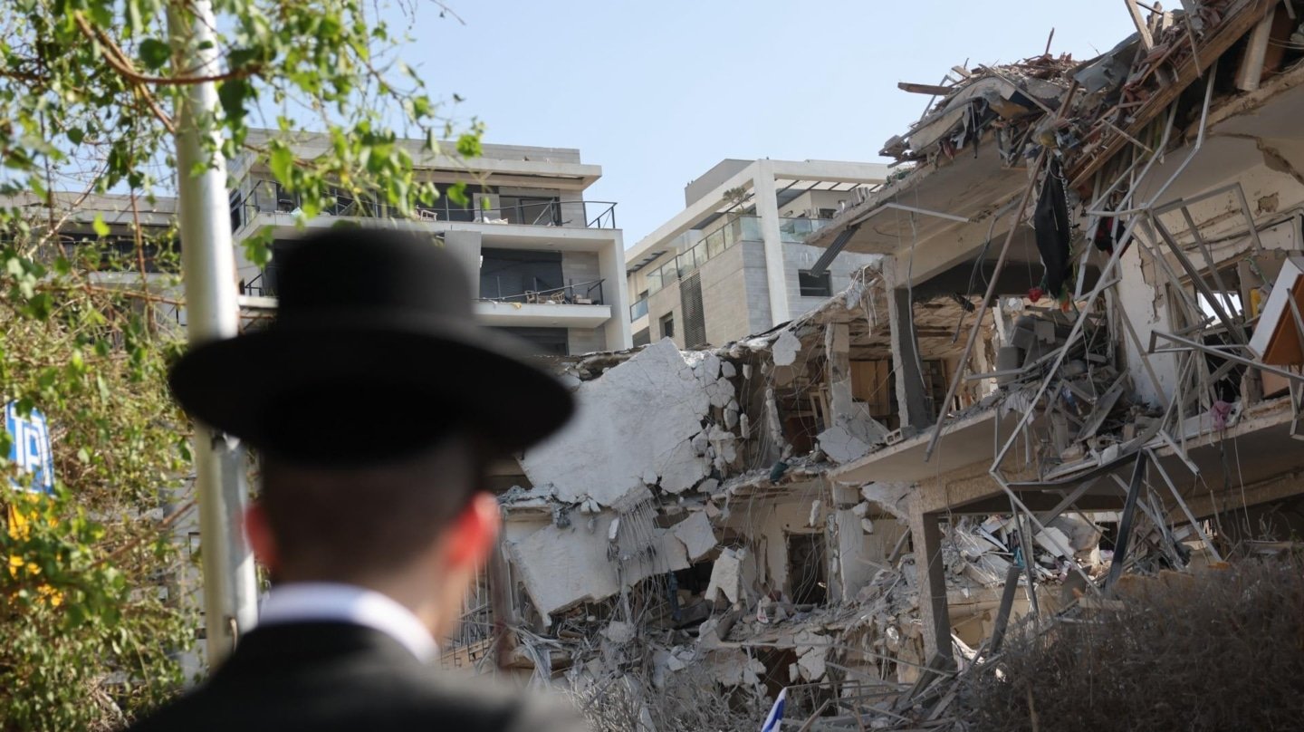 Un hombre contempla un edificio con un impacto de misil.