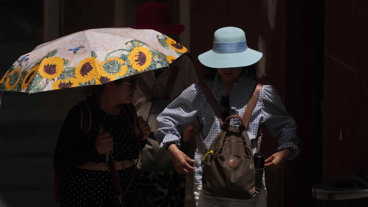 Unos turistas se resguardan con sombreros y sombrillas mientras caminan por Córdoba.