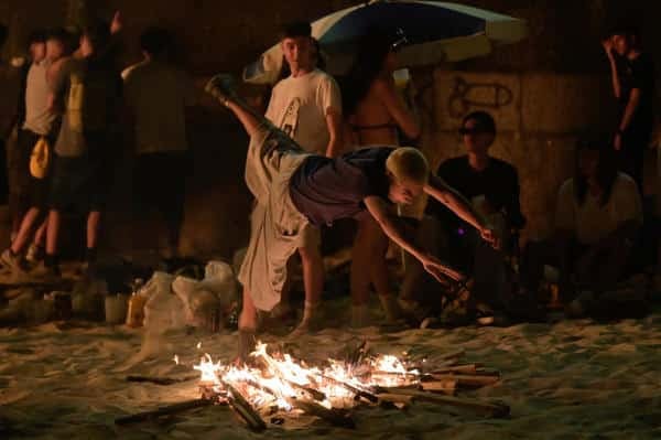 Un chico salta una de las hogueras encendidas en la playa coruñesa de Riazor