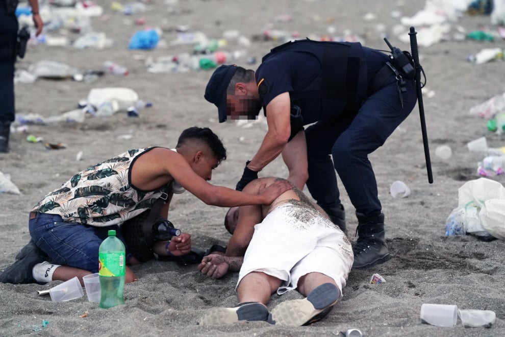 Un agente de la Policía Local atiende a una persona en la playa de La Malagueta