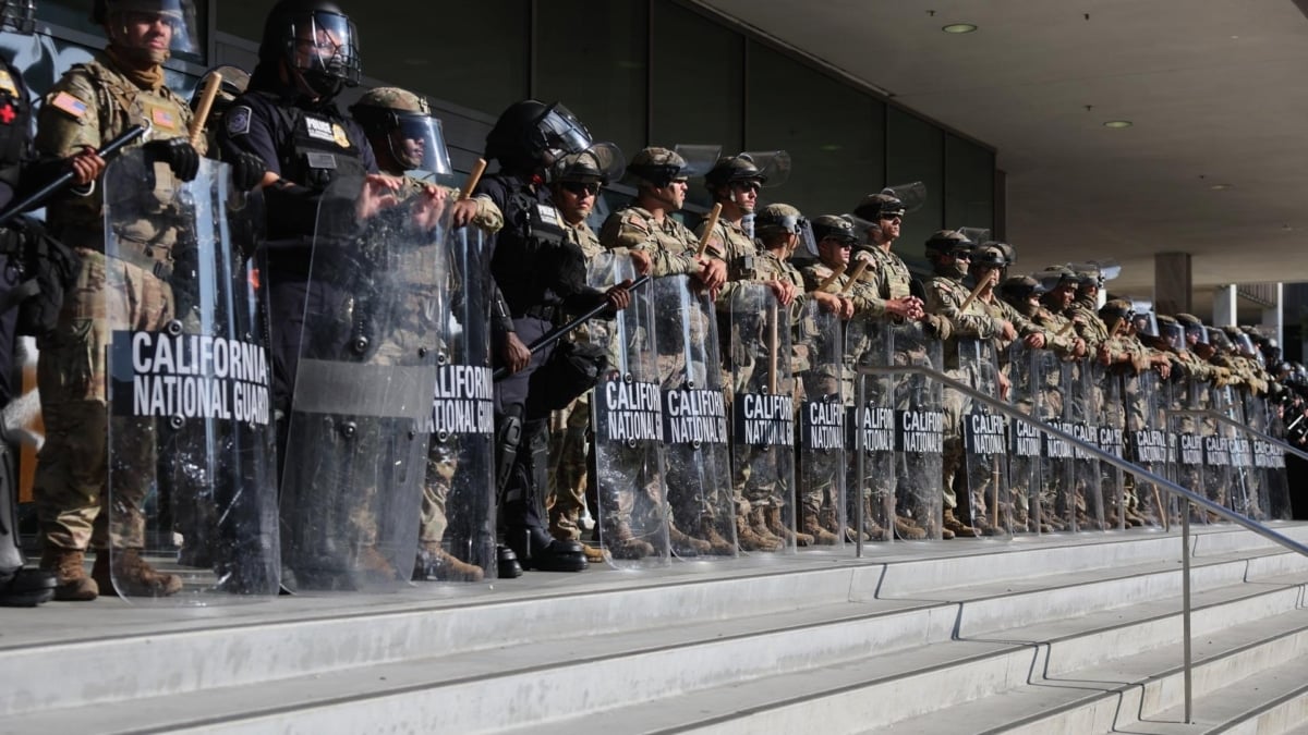 Agentes de la Guardia Nacional de California, de pie frente a un edificio federal al mismo tiempo que tiene lugar una protesta en Los Ángeles.