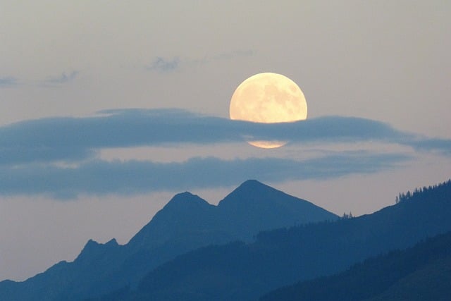 Luna llena apareciendo detrás de las montañas