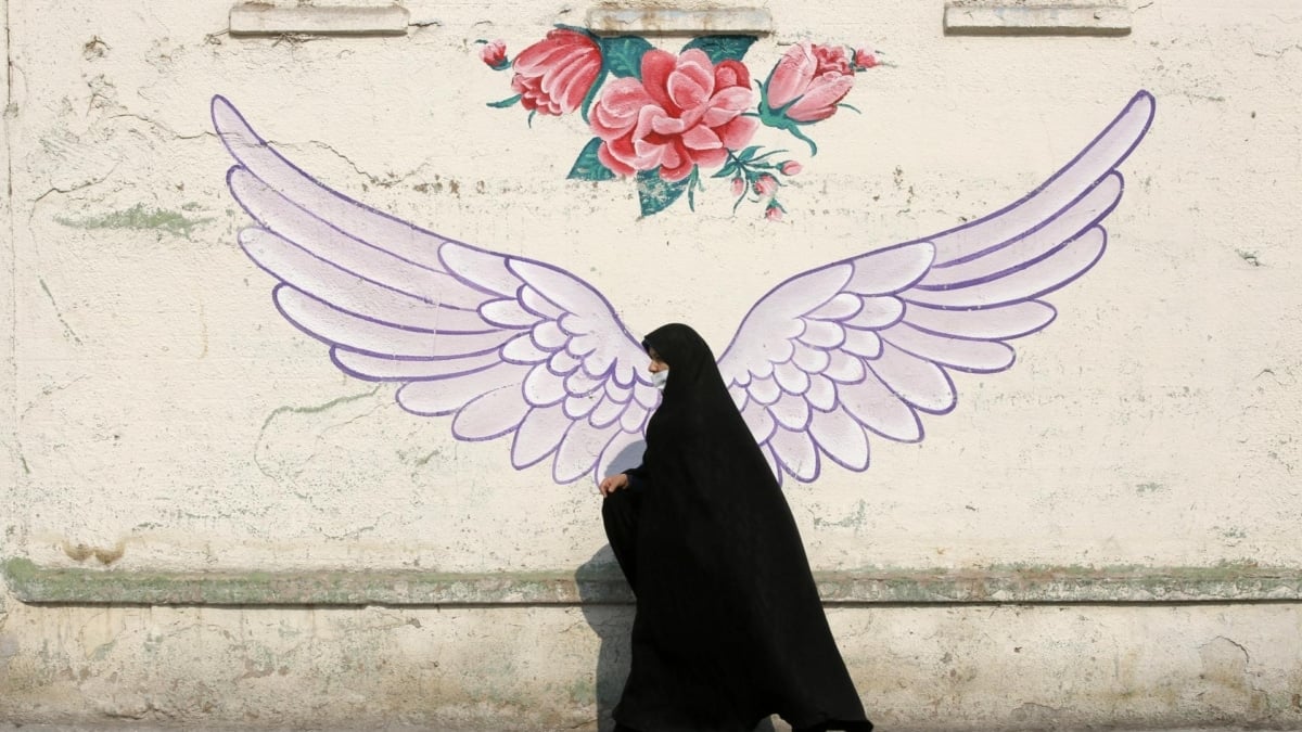 Una mujer iraní pasa por delante de un mural con unas alas en Teherán.
