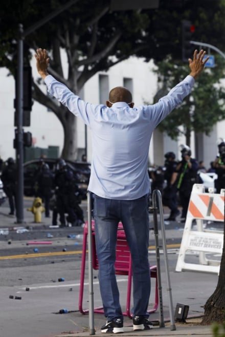 Un hombre que lleva un andador levanta los brazos en son de paz ante en medio de una protesta en Los Ángeles, California.