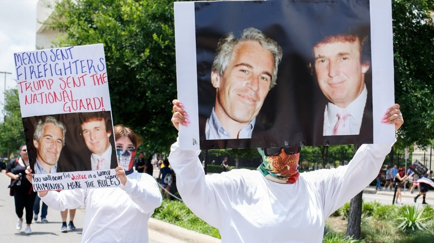 Dos mujeres llevan pancartas con una foto de Donald Trump y Jeffrey Epstein en una protesta en Dallas, Texas.