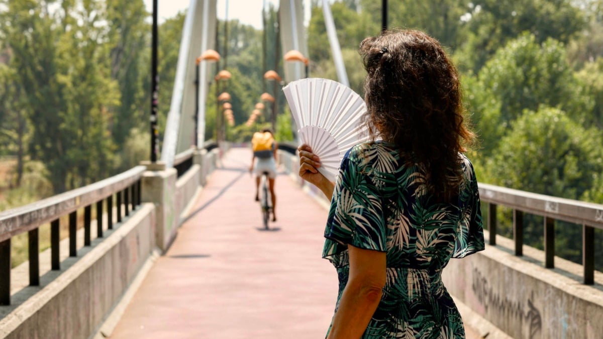 Una mujer se abanica a su paso por la pasarela sobre el Ebro en Logroño el pasado sábado.