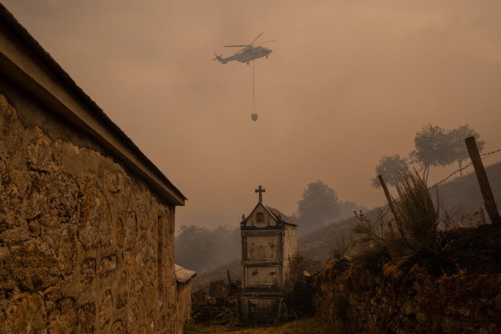  Un helicóptero de control de incendios sobrevuela el cementerio la localidad de Vilar durante el incendio forestal que permanece activo en Chandrexa de Queixa (Ourense). 