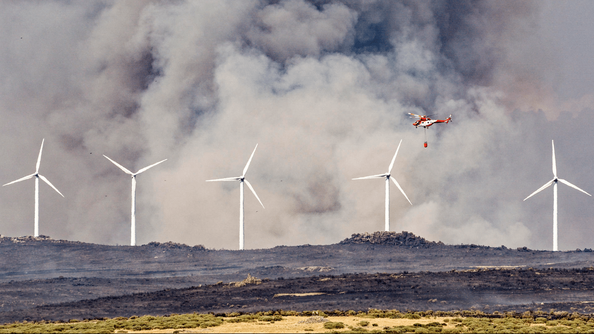 Un helicóptero trabaja en labores de extinción del incendio en las proximidades de Urraca-Miguel, barrio anexionado de Ávila capital, y cuyos vecinos han sido evacuados pasadas las 16 horas de este viernes por la proximidad de las llamas.