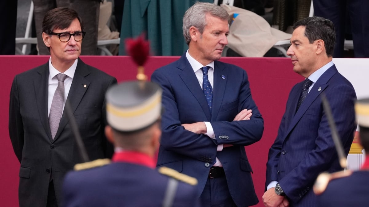 MADRID, 12/10/2025.- El presidente de la Generalitat, Salvador Illa; presidente de la Xunta de Galicia, Alfonso Rueda; y el presidente de la Junta de Andalucía, Juanma Moreno (de izda a dcha), antes del desfile de las Fuerzas Armadas con motivo de la Fiesta Nacional en la tribuna de autoridades este domingo en Madrid. EFE/Borja Sánchez-Trillo